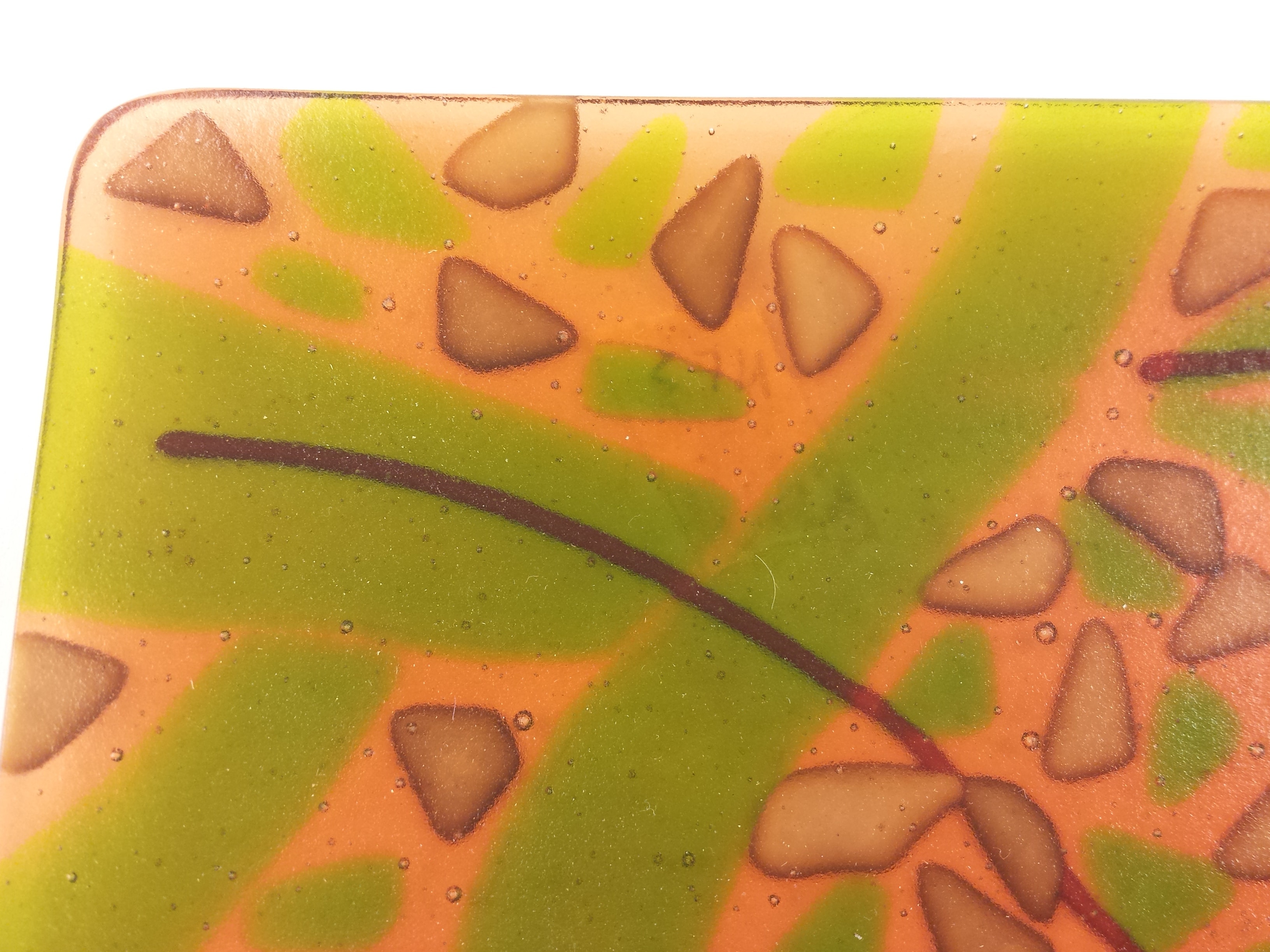 Closeup of a fused glass piece showing some reactions due to the chemical ingredient differences in the glass.