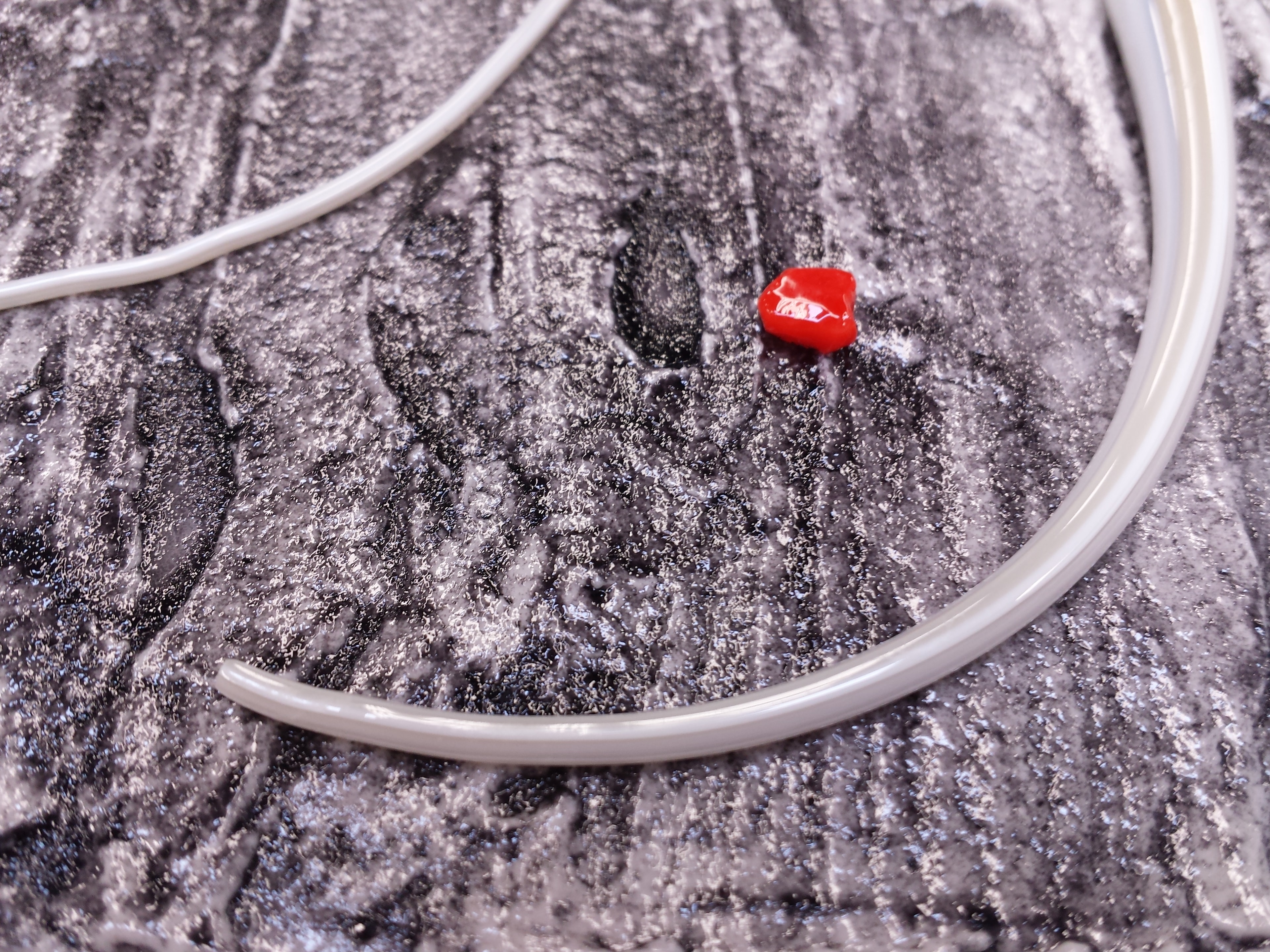Closeup of fused glass panel showing white stringer, red glass accent on a black & white textured glass surface.