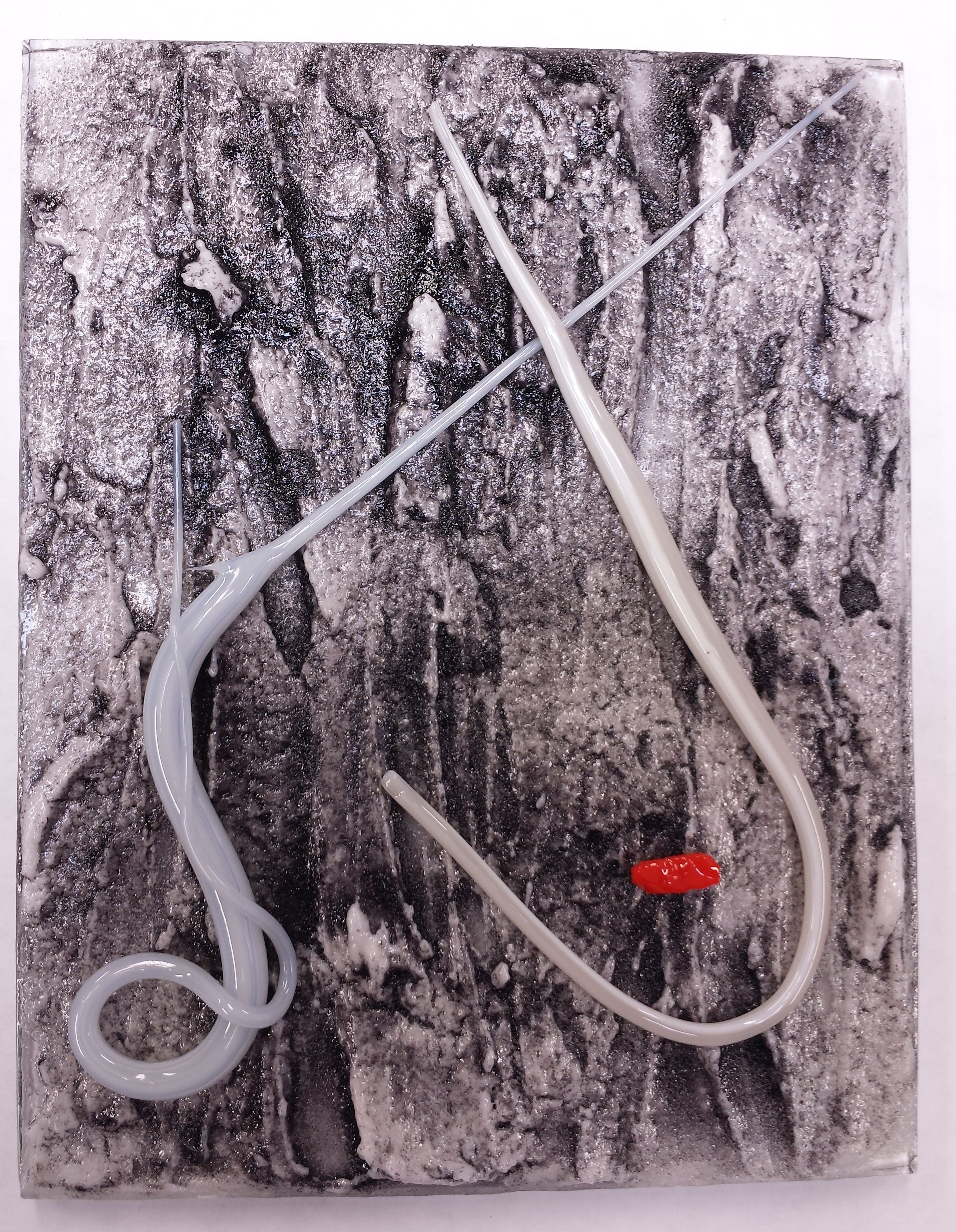 Fused glass wall panel with white stringer, forming flowing curves over a black & white textured glass surface.