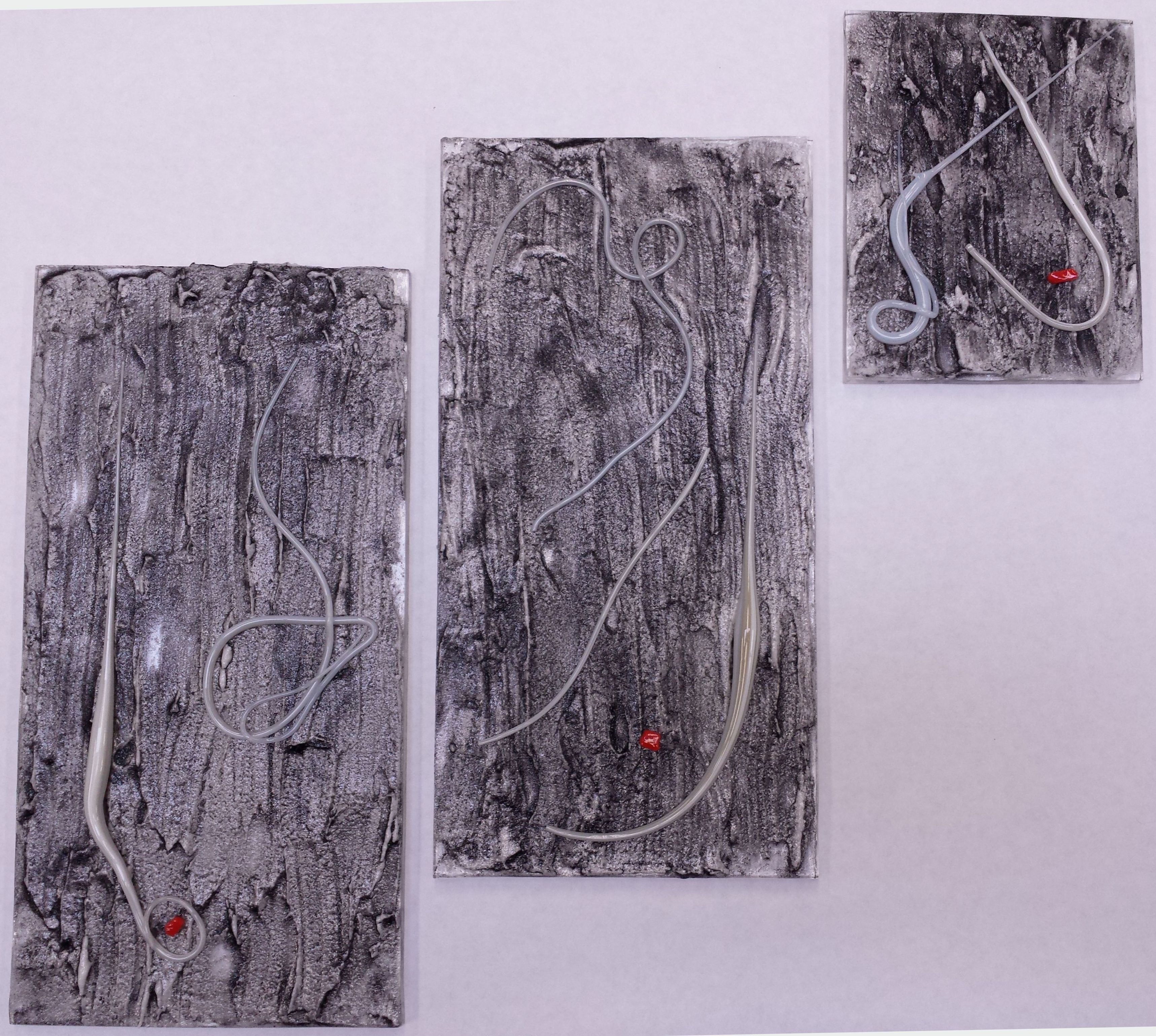 Textured Triptych of three fused glass panels — varying sizes with white glass stringer and red accents on black & white textured glass surface.